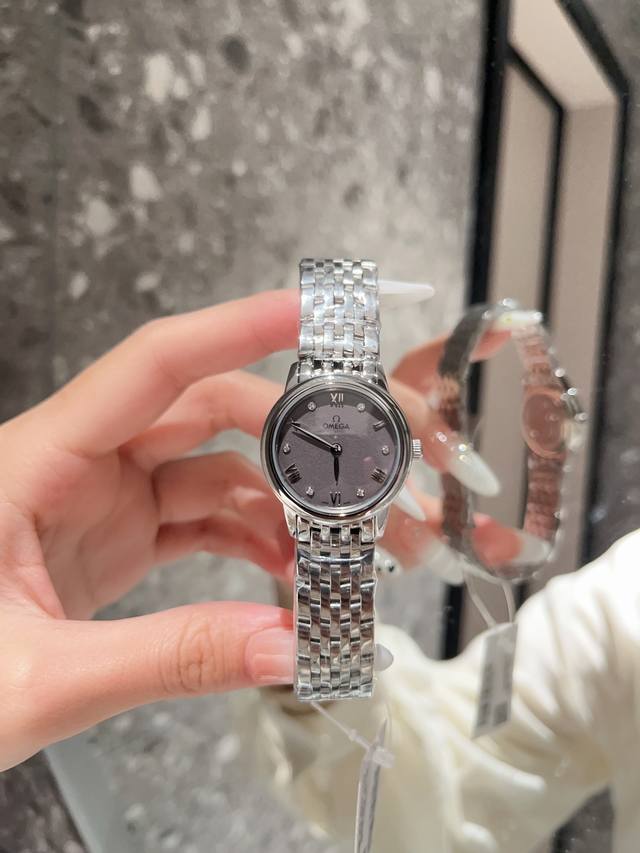 欧米茄第三代典雅女士腕表 新款典雅系列延续其经典雅致设计，以丰富多元的材质和配色呈现，表壳采用精钢打造，搭配镀铑指针，表盘经过Pvd处理更显细腻质感，加上真丁罗