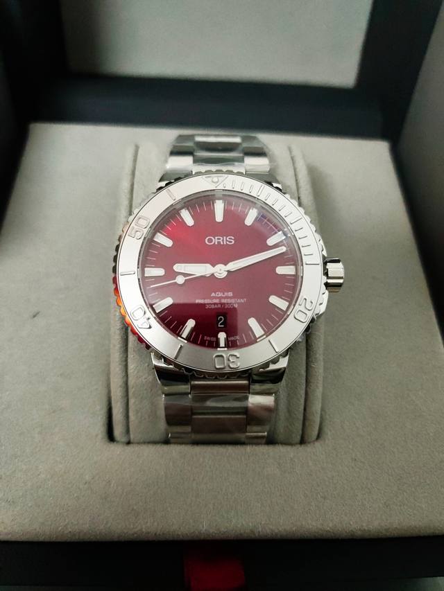 豪利时全新43.5毫米Aquis系列樱桃红日历腕表，樱桃红表盘装饰旭日纹，鲜艳活力，引人注目。银色镶贴时标、时分指针、乃至棒棒糖状秒针均嵌饰Super-Lumi