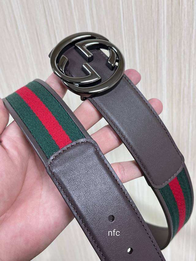 This double-sided belt features red and green webbing and dark brown cowhide lea