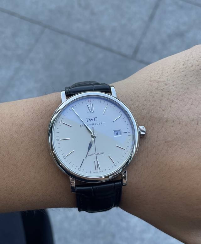 万国柏涛菲诺系列的简约三针日历款腕表，以其经典的美学设计和卓越的制表工艺闻名。此款腕表采用精致的蓝钢指针，在白色表盘上优雅地指示时间，搭配蓝色鳄鱼皮表带，不仅提