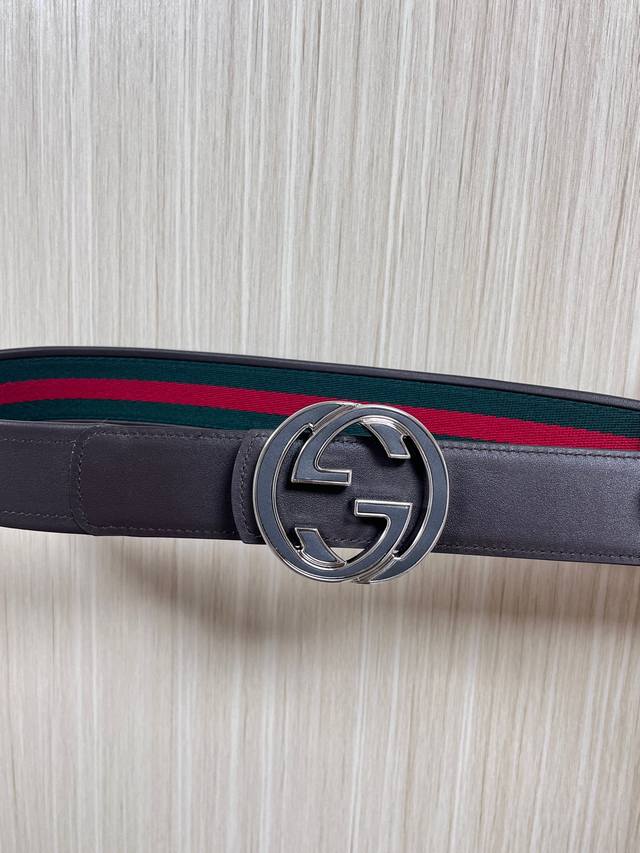 This reversible belt features red and green webbing and dark brown cowhide leath