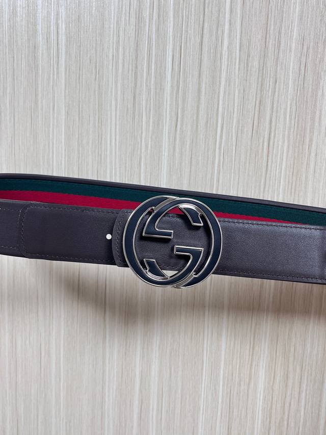 This reversible belt features red and green webbing and dark brown cowhide leath