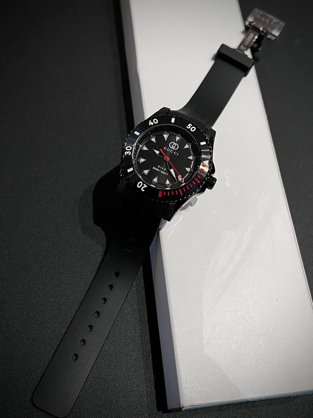 Gucci新款Dive系列从经典潜水表中撷取灵感，糅合经典款式与优越性能，活力动感之余不失优雅韵味。这款腕表搭载石英机芯。以黑色圈口搭配粉色表盘，配备粉色橡胶表